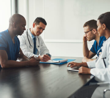 Medical team having a meeting with doctors in white lab coats and surgical scrubs