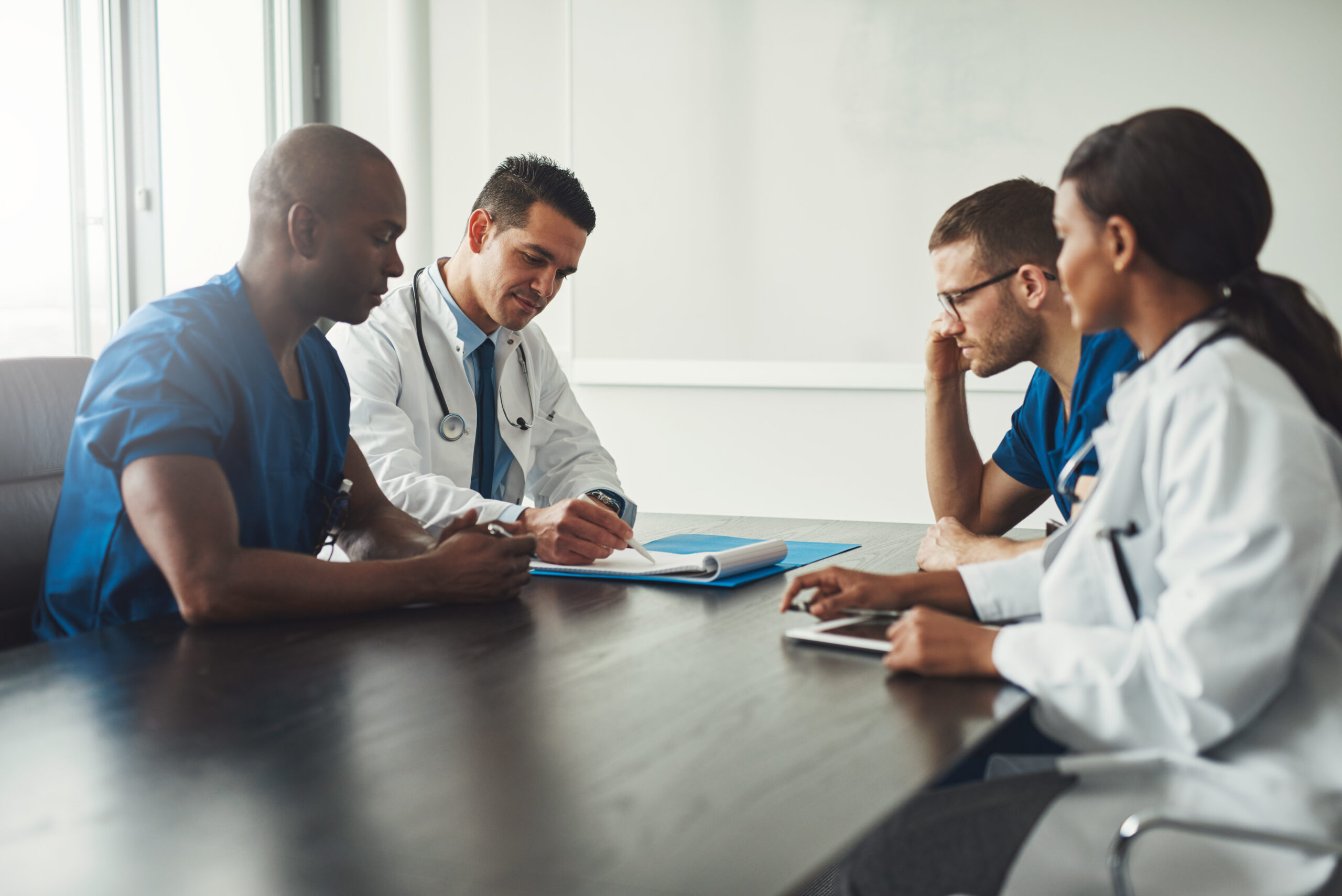 Medical team having a meeting with doctors in white lab coats and surgical scrubs